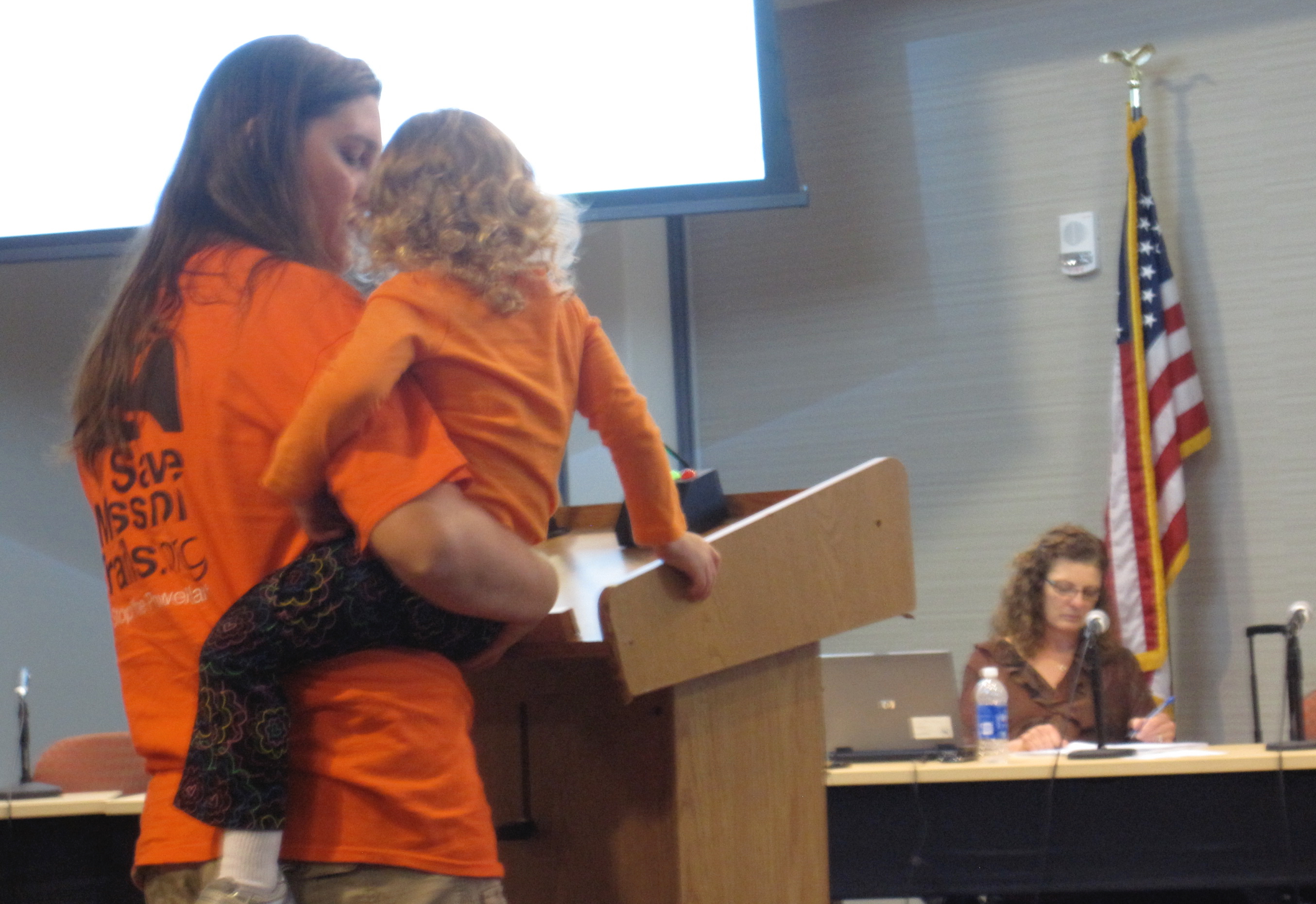 Speaker and child at podium at civic meeting